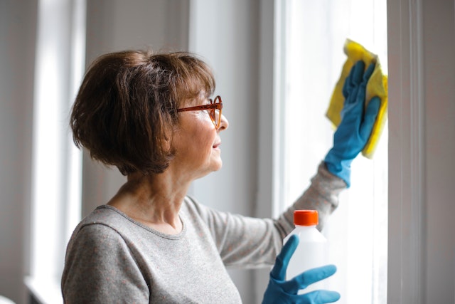 Person in blue gloves cleaning a window